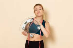 Frau Abnehmen mit Fitnesstraining Waage in der Hand